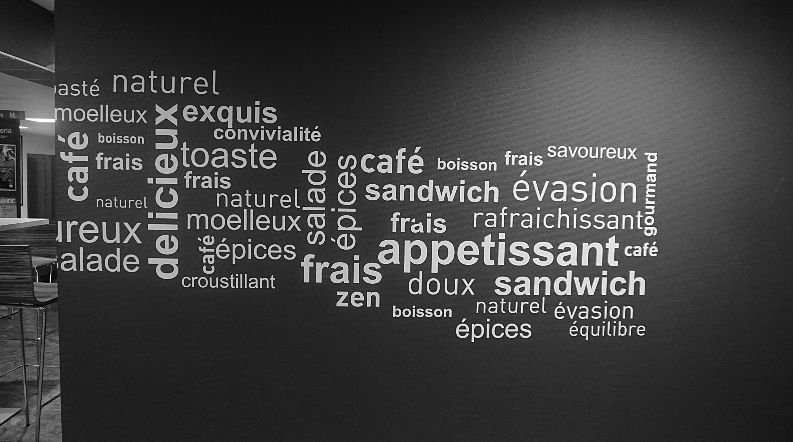 Monochrome word art on a cafe wall featuring French culinary terms.