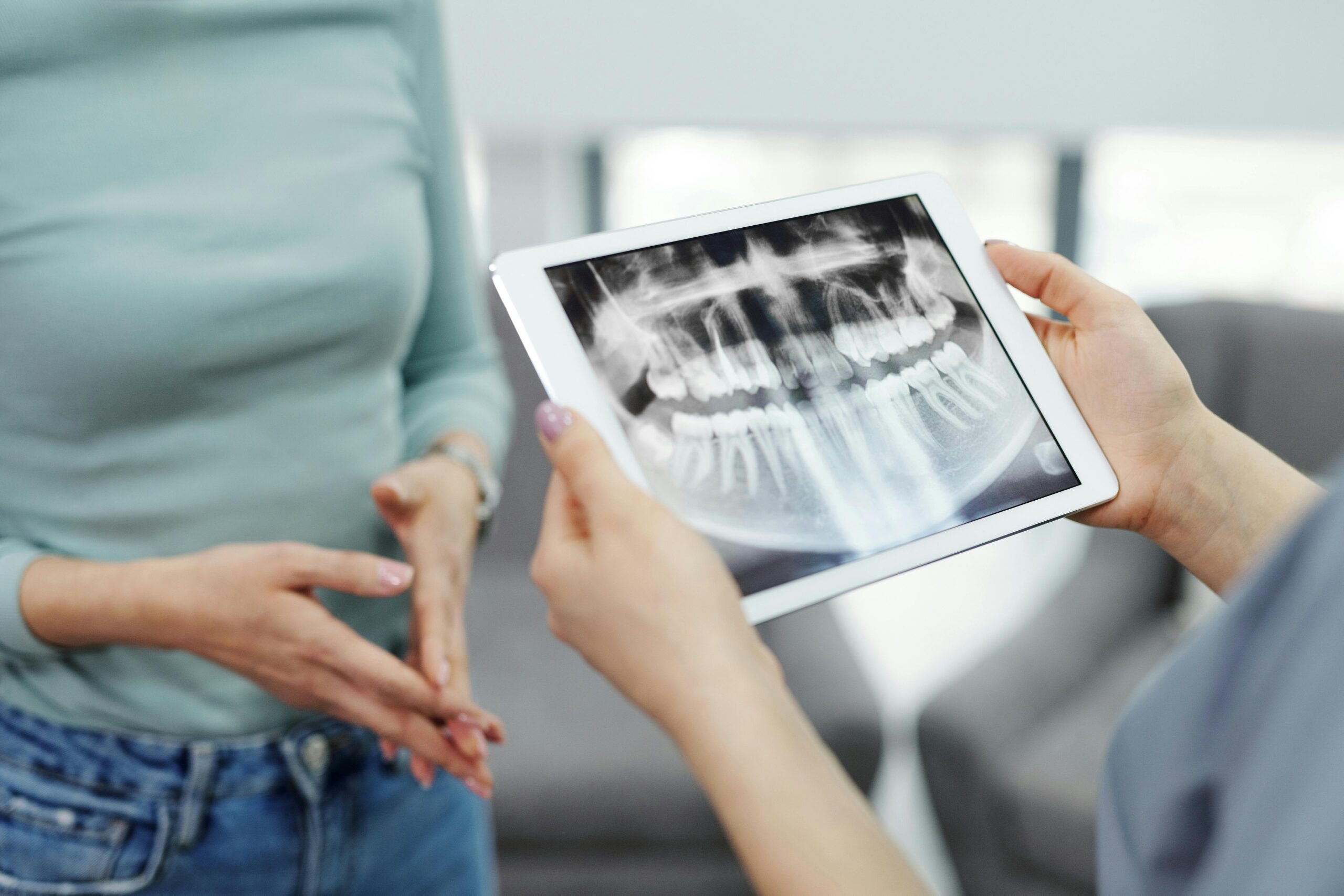 A dentist displays a dental x-ray on a tablet to a patient during a consultation.