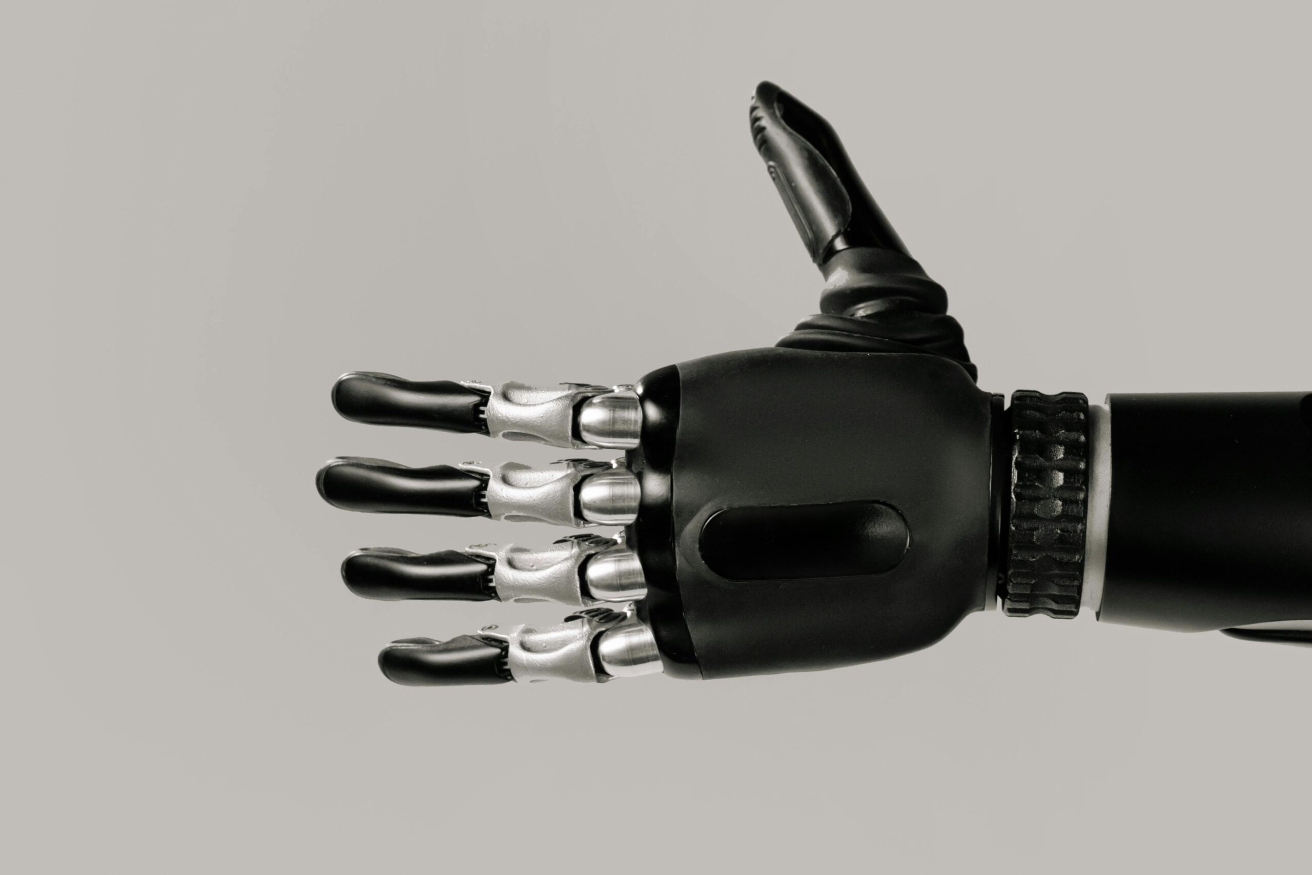 A detailed view of a sleek black and silver robotic prosthetic hand against a neutral background.
